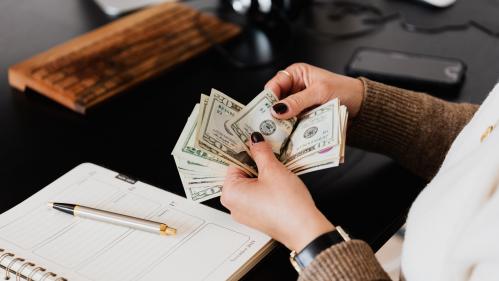 Woman counting and recording cash transactions